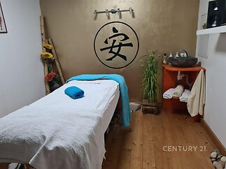 Pokoj pro wellness procedury s dřevěnou podlahou, dekorativní výzdobou a masážním stolem, klidné prostředí ideální pro relaxaci.