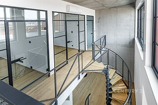 Světlá hala s parketovou podlahou a skleněnými příčkami, moderní točité schodiště, industriální styl, velká okna, klimatizace