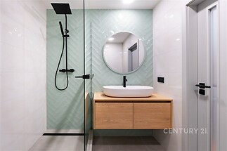 Moderní koupelna s velkou sprchou, dlažbou v rybí kosti a elegantním umyvadlem. Světlý prostor s minimalistickým designem a chladnými tóny.