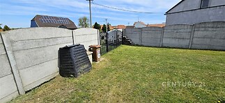 Zahrada s udržovaným trávníkem, betonovým plotem a bránou. Slunný prostor, ideální pro venkovní relaxaci, soukromí a klidná lokalita.