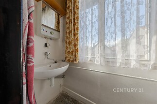 Koupelna s umyvadlem a dekorativní záclonou, původní vzhled, světlá místnost, vhodná pro renovaci.