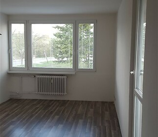 Světlý obývací pokoj s parketovou podlahou, velkými okny a moderní úpravou zajišťuje přirozené světlo a příjemnou atmosféru.