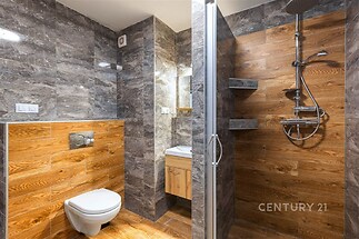 Moderní koupelna s dlažbou imitující dřevo, sprchovým koutem a vestavěným umyvadlem, kvalitní keramika a stylový design