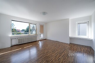 Světlý obývací pokoj s parketovou podlahou a velkými okny, moderní design a prostorný interiér pro maximální komfort bydlení