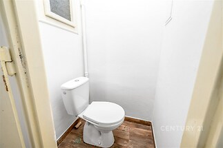 Malá toaleta s bílým toaletním přístrojem a dřevěnou podlahou, jednoduchý a čistý design