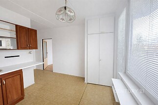 Světlá kuchyň s parketovou podlahou a vestavěnými skříněmi, doplněná velkými okny pro přirozené světlo, v moderním stylu.