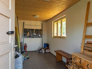 Úložný prostor s dřevěným stropem, dlažbou a vestavěnými regály, ideální pro dílnu nebo skladování.