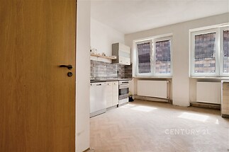 Světlá kuchyň s parketovou podlahou, moderními vestavěnými spotřebiči a velkými okny, která zajišťují dostatek přirozeného světla.