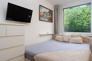 Světlá ložnice s parketovou podlahou, velkým oknem a moderním zařízením. Disponuje pohodlným lůžkem a nábytkem v neutrálních tónech.