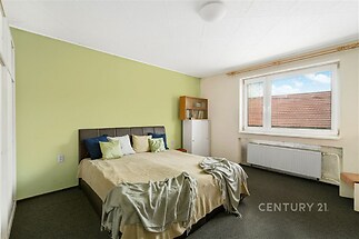 Prostorná ložnice, světlo z velkých oken, moderní nábytek, vestavěné skříně, světlé stěny, koberec, klidná atmosféra.