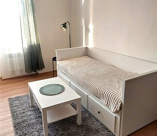 Světlý obývací pokoj s parketovou podlahou, velkými okny a moderním nábytkem.