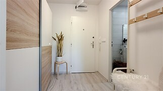 Vstupní chodba s moderními vestavěnými skříněmi, světlá dřevěná podlaha, čistý a elegantní design.