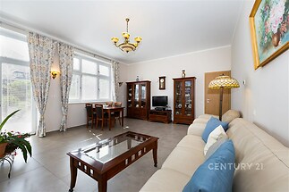 Světlý obývací pokoj s dlažbou, velkými okny a klasickým nábytkem, moderní dekorace a prostorný interiér.