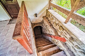 Venkovní schodiště z cihel a kamene, vedoucí do suterénu, se dřevěným zábradlím a vintage nástěnným světlem, nabízí rustikální styl.