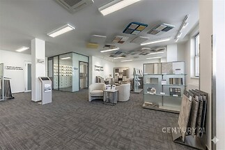 Pracovní showroom s moderním kobercem, velkým výběrem materiálů a vzorků, světlý interiér s velkými okny a skleněnými příčkami.