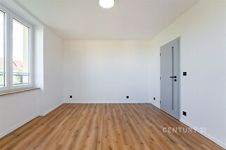 Prázdný pokoj s parketovou podlahou, velkými okny a moderními dveřmi, světlá atmosféra vhodná pro osobní úpravy.