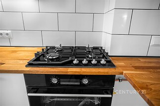 Kuchyňská linka s moderním plynovým sporákem, dřevěnou pracovní deskou a bílými obklady, ideální pro vaření a přípravu jídla.