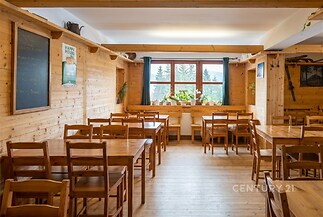 Jídelna s dřevěným obložením, světlá parketová podlaha, velká okna s výhledem, rustikální stylový nábytek, útulná atmosféra.