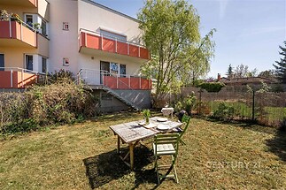 Udržovaná zahrada s venkovní terasou, stůl s židlemi, vhodné pro relaxaci. Klidná lokalita, ideální pro rodinné bydlení.