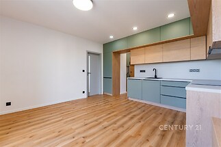 Moderní kuchyň s parketovou podlahou, vestavěné skříně a světlé dřevěné povrchy, minimalistický design a prostorný interiér.