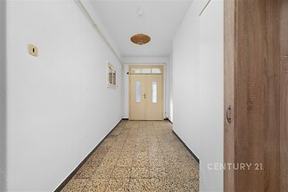 Chodba s dlažbou, světlá místnost s velkými dveřmi, neutrální bílá výmalba, ideální pro renovaci nebo modernizaci.