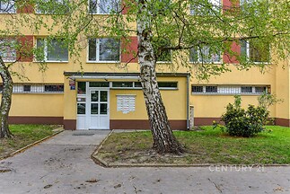 Exteriér obytného domu s moderní fasádou, velkými okny a udržovanou zelení, oplocen výhledem na vstupní dveře a okolní stromy.