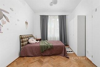 Ložnice s parketovou podlahou a vestavěnými skříněmi, světlá s velkými okny a moderním nábytkem.