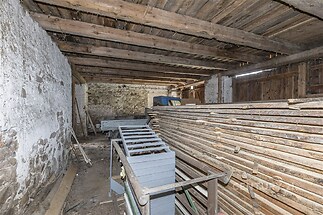 Prostorná stodola s rustikálním dřevěným stropem, kamennými zdmi a přírodním povrchem, ideální pro skladování nebo přestavbu.