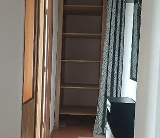 Úzká předsíň s dlažbou a vestavěnými skříněmi, moderní design s dřevěnými detaily a velkým zrcadlem.