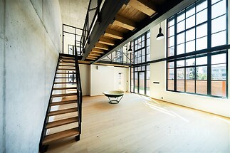 Světlý obývací pokoj s moderním designem, parketovou podlahou a velkými okny, poskytujícími dostatek přirozeného světla, nabízí otevřený prostor.