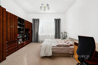 Prostorná ložnice s kobercem, velkými okny a vestavěnými skříněmi. Světlé stěny dodávají prostoru moderní a vzdušný vzhled.