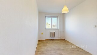 Světlý pokoj s parketovou podlahou a moderním osvětlením, velké okno poskytuje dostatek denního světla, vhodný pro úpravy nebo přizpůsobení.