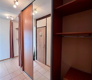 Prostorná chodba s dlažbou, vestavěnými skříněmi a moderním osvětlením.