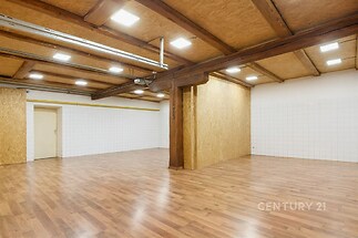 Prostorný obývací pokoj s parketovou podlahou, dřevěnými trámy a moderními stropními světly, ideální pro flexibilní uspořádání interiéru.