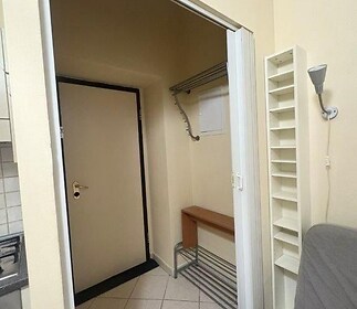 Vstupní chodba s dlažbou, světlými stěnami a vestavěnými úložnými prostory, nabízí praktické řešení pro menší byty