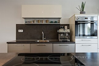 Moderní kuchyň s vestavěnými spotřebiči, tmavou pracovní deskou a lakovanými skříňkami, stylový design a kvalitní materiály.