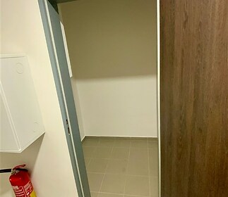 Úložný prostor s dlažbou, ideální pro skladování, se světlými stěnami a moderními dveřmi.