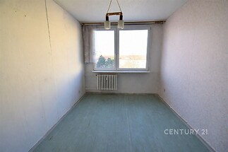 Prázdná ložnice s velkým oknem, parketová podlaha, potřebuje rekonstrukci, minimalistický styl