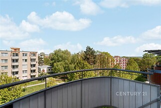 Výhled z balkonu s moderním zábradlím, zelení a panoramatickým výhledem, ideální pro relaxaci.
