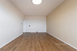 Úzká místnost s parketovou podlahou, světlé stěny, minimalistické dveře, moderní styl, vhodná pro vestavěné skříně nebo pracovnu.