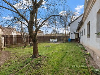 Prostorná zahrada s udržovaným trávníkem, dřevěným plotem a vzrostlým stromem, ideální pro rodinné aktivity nebo relaxaci na čerstvém vzduchu.