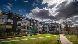 Moderní bytový komplex s dřevěnými balkony a velkými okny, světlý a nově postavený, nabízí kvalitní bydlení v klidné lokalitě.