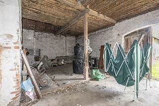 Pracovní dílna s betonovou podlahou, dřevěným stropem a kamennými zdmi, ideální pro skladování nebo renovaci, prostor nabízí rustikální charakter.
