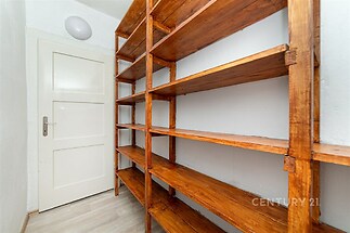 Úložný prostor s dřevěnými regály, laminátová podlaha, bílá stěna, ideální pro skladování v moderním bytě.