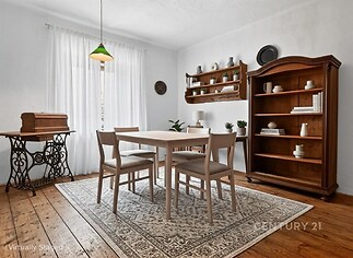 Jídelna s dřevěnou podlahou, vintage nábytkem a velkým oknem, světlý prostor s tradičním dekorem, ideální pro rodinné stolování.