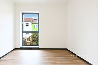 Světlý pokoj s parketovou podlahou, velkým oknem a moderním designem, nabízí skvělou možnost pro osobní úpravy nebo vybavení.