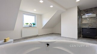 Prostorná koupelna, moderní dlažba, střešní okno, elegantní umyvadlová skříňka, světlý interiér, skvělé přirozené osvětlení.