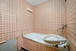 Koupelna s vanou, rustikální obklady na stěnách, jedinečný retro styl, což nabízí potenciál pro renovaci nebo modernizaci prostoru.