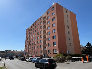 Vícepatrový bytový dům s růžovou fasádou, plastová okna a parkování v ulici před budovou, vhodné pro klidné městské bydlení