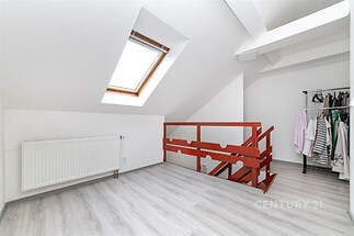 Podkrovní prostor s laminátovou podlahou a střešním oknem, světlý interiér s otevřeným schodištěm a závěsnou šatní tyčí.